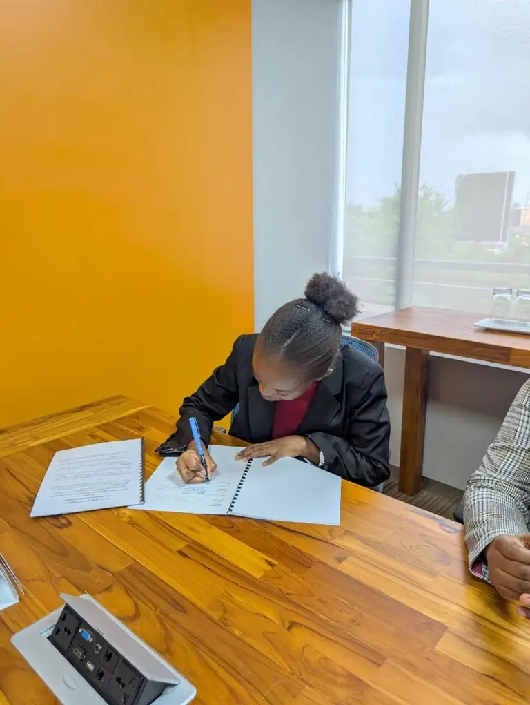 Michelle Mugo signing documents during a professional meeting